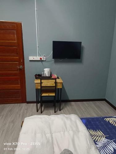 a bedroom with a bed and a table with a tv at ROO STAy TOK WAN 1 in Kampong Nail