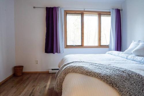 a bedroom with a bed and a window with purple curtains at Lovely Liberty Chalet On the Waterfront in Liberty