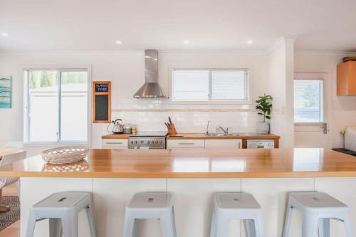 a kitchen with a wooden counter top and stools at Almonta Escape - COFFIN BAY - Perfect for couples or families in Coffin Bay