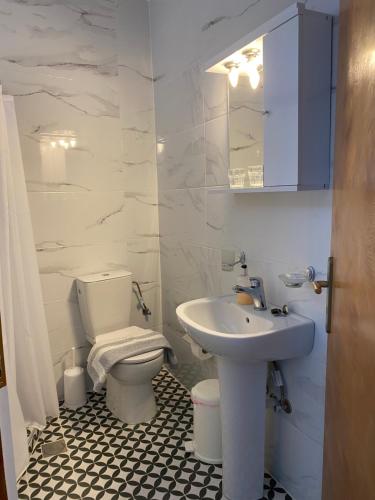 uma casa de banho branca com um lavatório e um WC em Garden House em Chora Sfakion