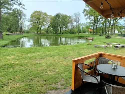 un patio con mesa, sillas y un estanque en Domek nad stawem, en Golczewo
