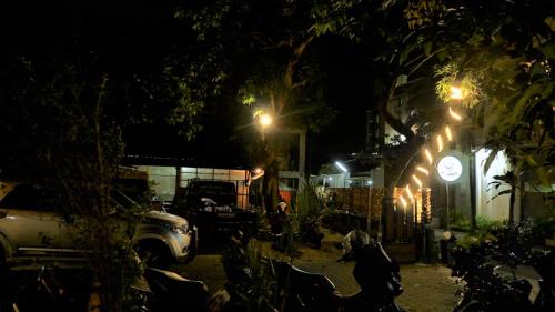 a street at night with a tree and a clock at Sleepy Raccoon Hostel in Yogyakarta