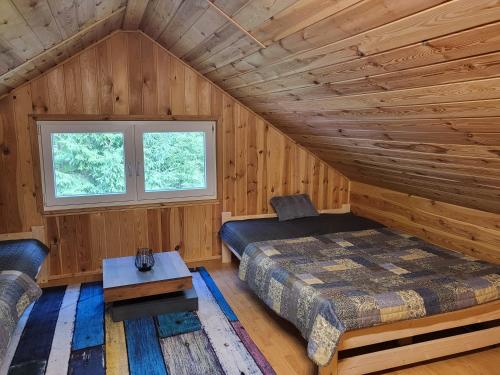 1 dormitorio en una cabaña de madera con 1 cama y 1 mesa en Duży domek przy lesie, 