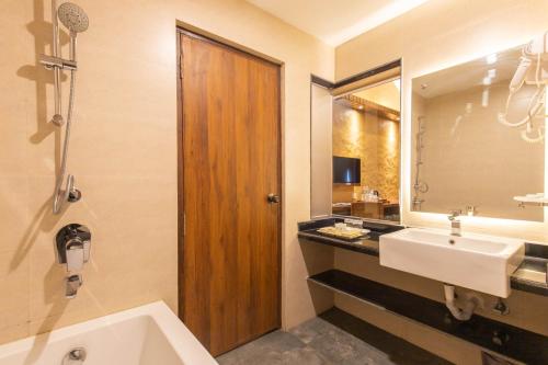 a bathroom with a sink and a mirror and a tub at Bar Peepal Resort in Pokhara