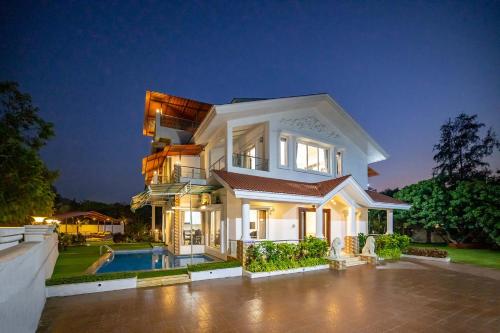 a large white house with a pool in front of it at Casa Serenity by StayVista - Relax with a pool, lawn, and inviting jacuzzi in Lonavala