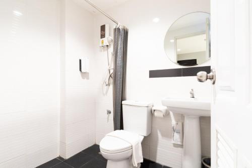 a white bathroom with a toilet and a sink at North Inn Town Chiangmai in Chiang Mai