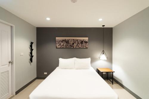 - une chambre avec un lit blanc et un mur noir dans l'établissement North Inn Town Chiangmai, à Chiang Mai