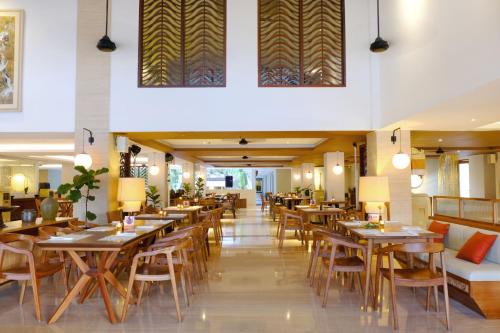 a dining room with wooden tables and chairs at The Magani Hotel and Spa in Legian