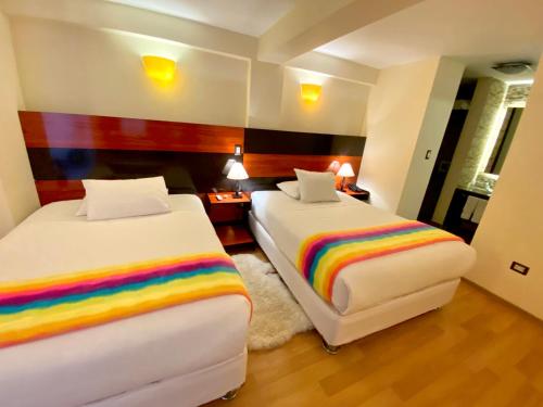 a room with two beds with rainbow sheets at Mistico San Blas Boutique in Cusco