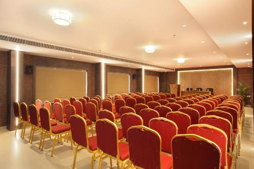 a conference room with red chairs and a podium at HOTEL MARIA PARK in Mūvattupula