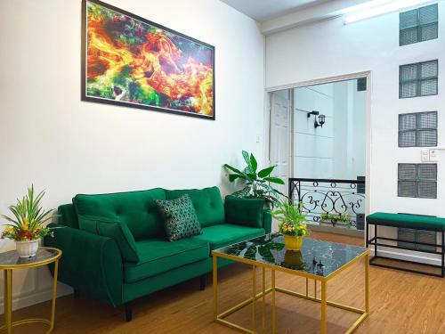 a living room with a green couch and a painting on the wall at La Vie - Saigon Homestay in Ho Chi Minh City