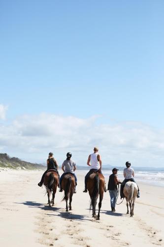 a group of people riding horses on the beach at Elements Of Byron in Byron Bay