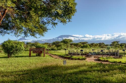 a park with a sign and mountains in the background at Amboseli Sopa Lodge in Amboseli