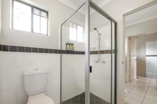 a bathroom with a toilet and a glass shower at Alara Motor Inn in Mackay