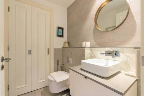 een badkamer met een wastafel, een spiegel en een toilet bij Stunning Apt with Spacious Terrace Old Town Dubai in Dubai