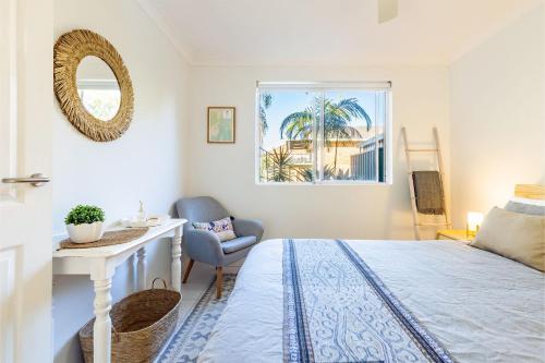 Un dormitorio con una cama, una silla y un espejo. en Fingal Bay Coastal Retreat 1 12 Marine Dr fantastic ground floor duplex, en Fingal Bay