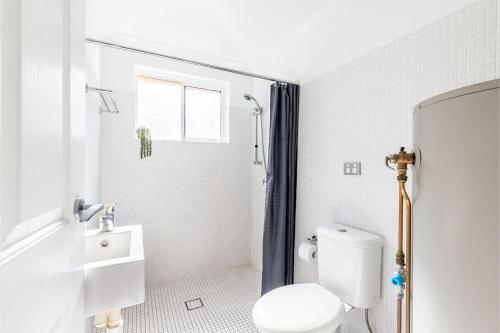 a white bathroom with a toilet and a sink at Fingal Bay Coastal Retreat 1 12 Marine Dr fantastic ground floor duplex in Fingal Bay