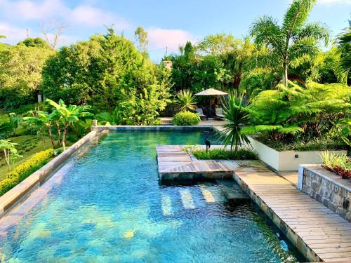 an infinity pool with a wooden walkway in a garden at Chamarel Mountain chalets in Chamarel