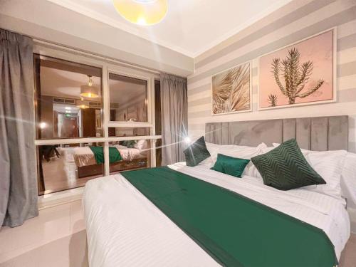a bedroom with a large bed with green pillows at Cosmos Living Stylish Studio Near Marina in Dubai