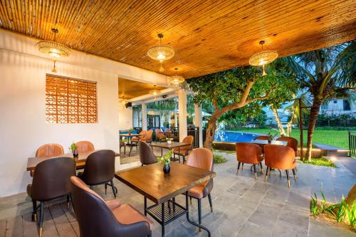 a patio with tables and chairs and a pool at Sunkised Paddy Hoi An Villa in Hoi An