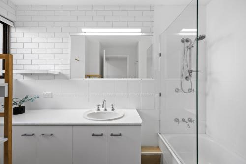 a white bathroom with a sink and a mirror at Beachside Views 2 Bedroom Apartment Mooloolaba in Mooloolaba