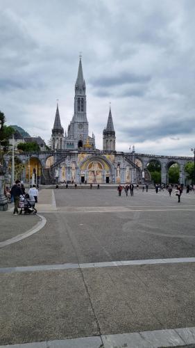 un grand bâtiment avec une tour d'horloge en haut dans l'établissement Castèléma - Appartement proche du sanctuaire, à Lourdes