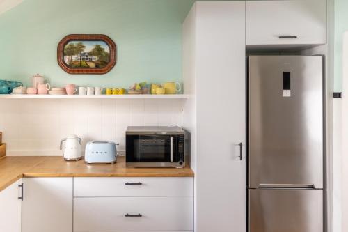 een keuken met witte kasten en een roestvrijstalen koelkast bij Boho Chic Apartment Stellenbosch in Stellenbosch