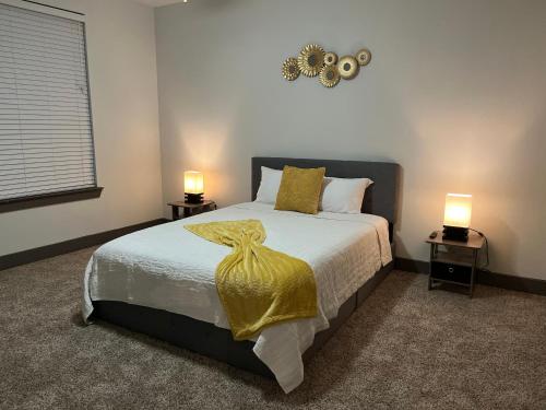 een slaapkamer met een bed met een gele deken en 2 lampen bij Comfy Abode near Bush Airport in Houston