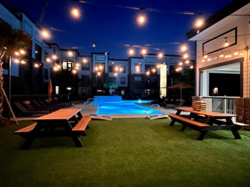 eine Terrasse mit Bänken und ein Pool in der Nacht in der Unterkunft Comfy Abode near Bush Airport in Houston
