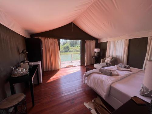 1 dormitorio con 2 camas y ventana grande en Ndlovu Addo River Lodge, en Kirkwood