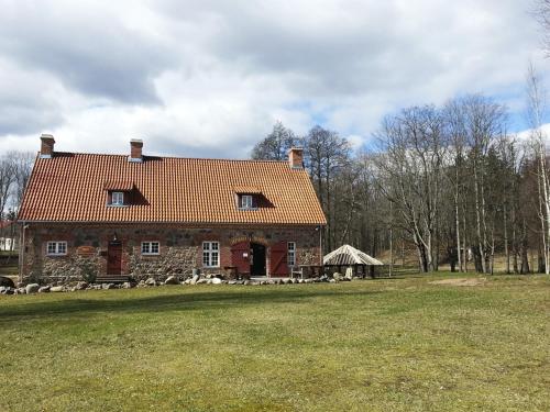 an old stone house with a red roof on a field at Sepikoja Guest House in Alatskivi