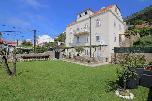 a large white building with a yard in front of it at Vicina Summer Apartments in Dubrovnik