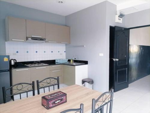 eine Küche mit einem Tisch und Stühlen sowie eine Küche mit einer schwarzen Tür in der Unterkunft KARON STUDIO APARTMENT in Ka Rorn
