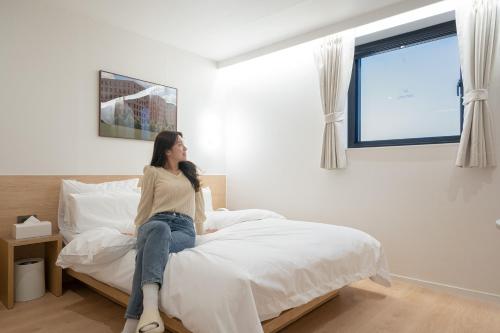 a woman sitting on a bed in a bedroom at Aank Hotel Cheongju Uam 1st in Cheongju