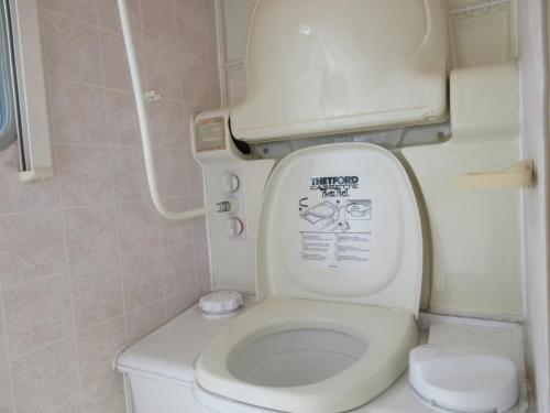 a bathroom with a toilet with the lid up at DogrunCafe & Resorts JENNIE West-Karuizawa in Miyota