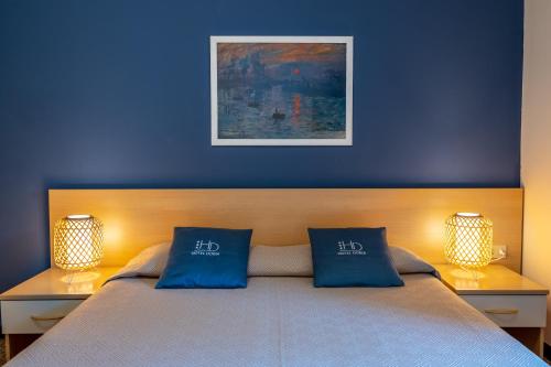 a blue bedroom with a bed with two blue pillows at Hotel Doria in Cavi di Lavagna