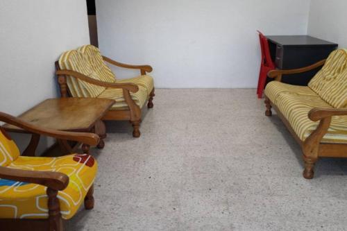 3 Stühle und ein Tisch in einem Zimmer in der Unterkunft NTC Homestay at Parit Buntar in Parit Buntar