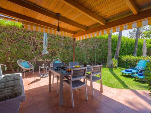 a patio with a table and chairs under a wooden pergola at Bungalow Tunos Maspalomas in San Bartolomé