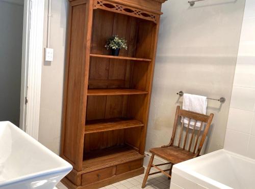 a wooden book shelf in a bathroom with a chair at The Edward Townhouse 157 - Steps to Town in Orange