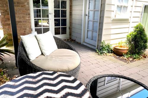 a wicker chair with pillows sitting on a patio at The Edward Townhouse 157 - Steps to Town in Orange