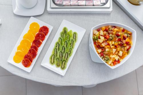 four plates of food on a table with fruits and vegetables at Hotel Doria in Cavi di Lavagna