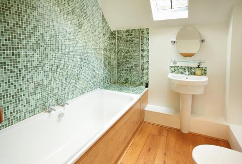 a bathroom with a tub and a sink and a toilet at Fron Cottage in Llangynog