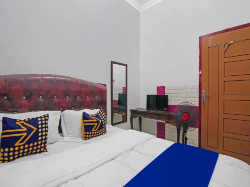 Schlafzimmer mit einem Bett und einem Schreibtisch mit einem Spiegel in der Unterkunft SPOT ON 92570 Putri Guest House Syariah in Pekanbaru