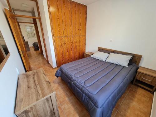1 dormitorio con 1 cama con pared de madera en NTORAS Holiday Home en Pafos