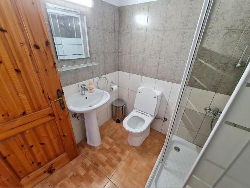 Un baño con inodoro, lavabo y ducha. en NTORAS Holiday Home, en Pafos