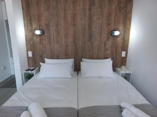 1 cama con 2 almohadas blancas y cabecero de madera en Walvis Bay Wind Beggars en Walvis Bay
