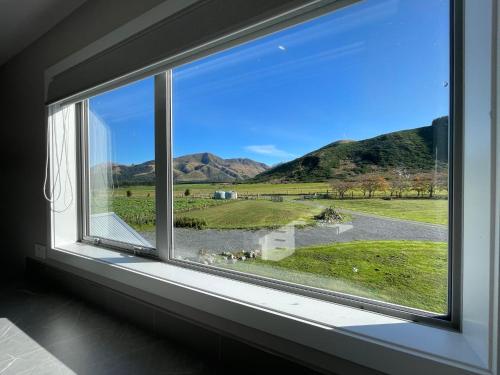 a window with a view of a field and mountains at Pudding Hill Lodge & Chalets in Mount Hutt