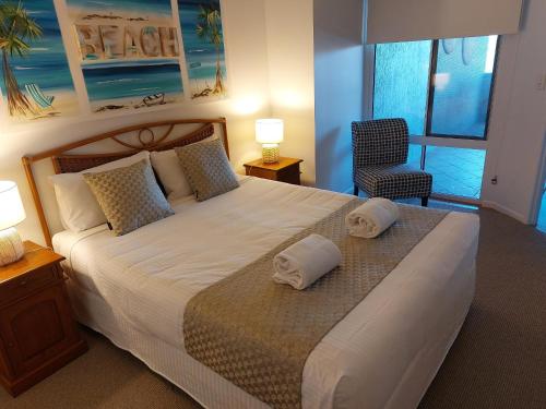 a bedroom with a large bed with two towels on it at Sandy Shores Holiday Units in Caloundra
