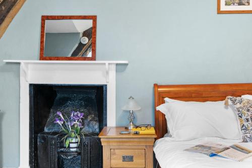 a bedroom with a bed with a fireplace and a mirror at Bellamarsh Farm B&B in Newton Abbot