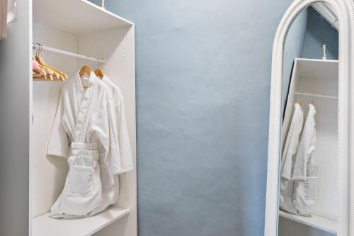 a wardrobe with white clothes and a mirror at Bellamarsh Farm B&B in Newton Abbot